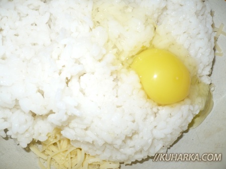 К рису добавить половину сыра, вбить яйцо